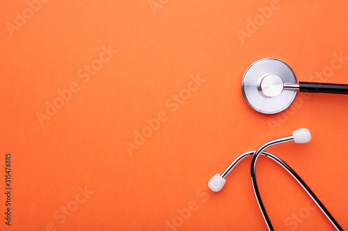 Medical stethoscope on orange background. Health care concept photo