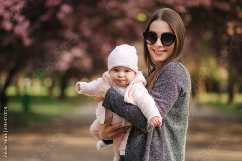Portrait of mother and her little baby girl. Beautiful mom and cute baby. Mother hud her daughter. Baby dressed in peanch colour hat and smile photo
