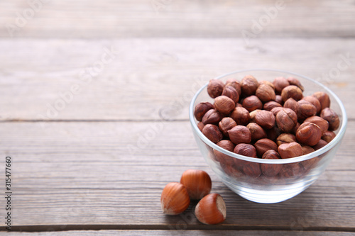 Delicious hazelnut in the wooden bowl on grey background