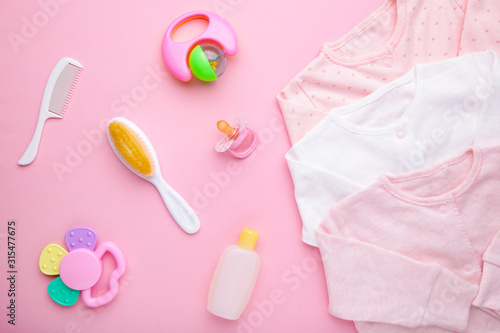 Baby clothes with a shower accessories on a pink background