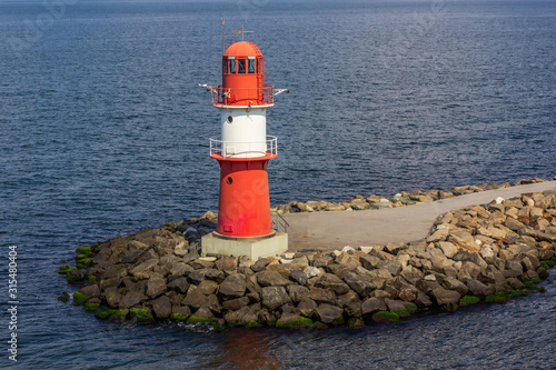 Typical Small Striped Lighthouse surrounded by the sea.