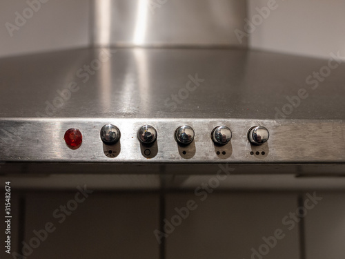 Metallic buttons atop kitchen stove close up