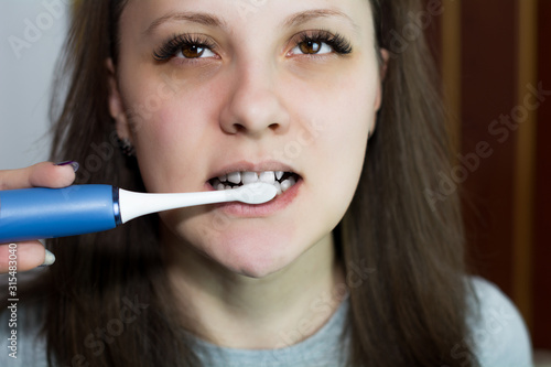 Woman brushes her teeth with an electric toothbrush