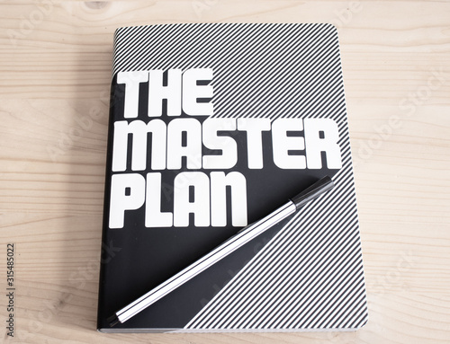 Master Plan word with Notepad and green plant on wooden background photo