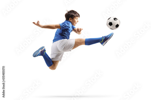 Boy in a sports jersey jumping and kicking a soccer ball photo