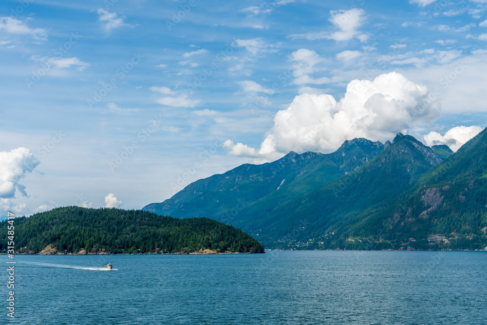 View over inlet, ocean and island with boat and mountains in beautiful British Columbia. Canada.