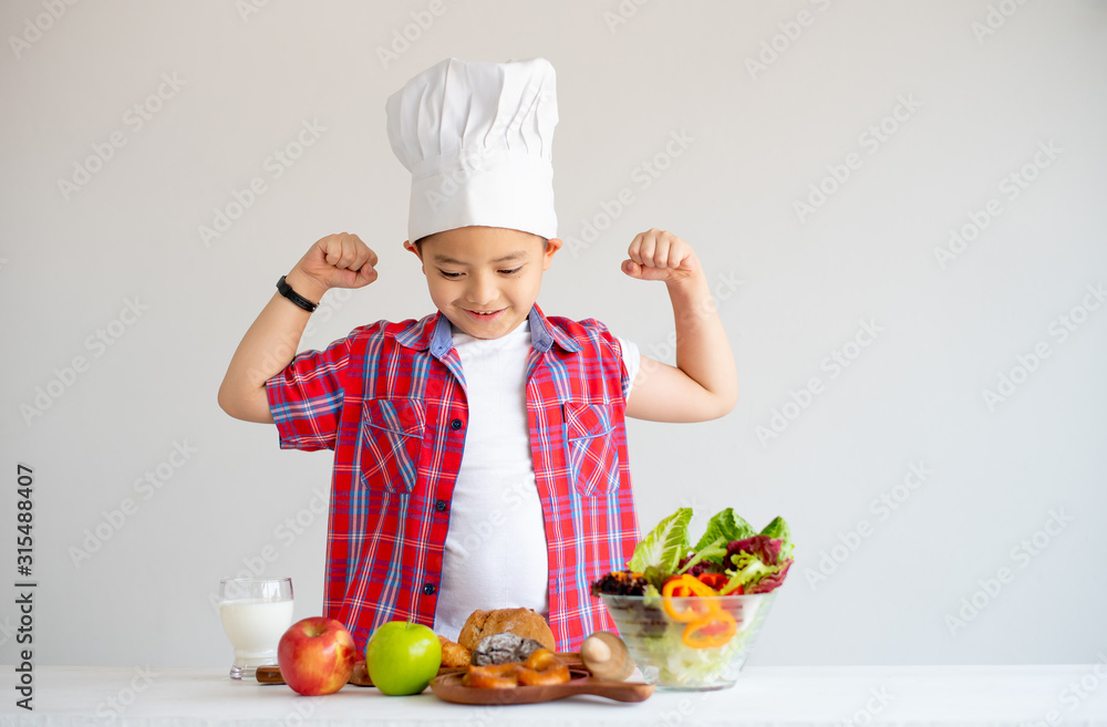 Asian red shirt little boy show action of feel stronger with various types of vegetable and fruits with healthy food concept for children. Asian red shirt little boy show action of feel stronger with various types of vegetable and fruits with healthy food concept for children.