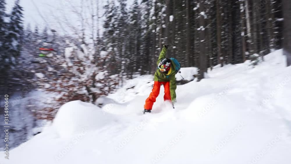 snowboarder rides between the trees and falls down over on the slope snowboarder rides between the trees and falls down over on the slope