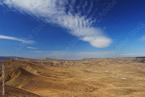 A cloud hangs over the sunlit hilly valley, like the trail of a UFO flight. © Игорь Афонченков