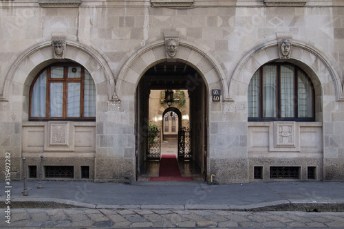 sober fa  ade of an old building  arched entrance leading to an elegant arcaded courtyard