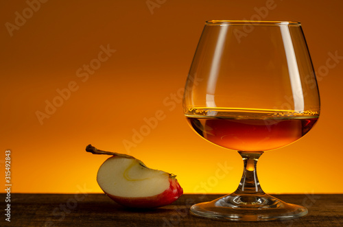 glass of Calvados Brandy and red apples on wooden table photo