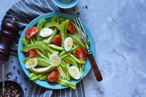 Vitamin salad with avocado, egg, cherry tomatoes on a concrete background. photo