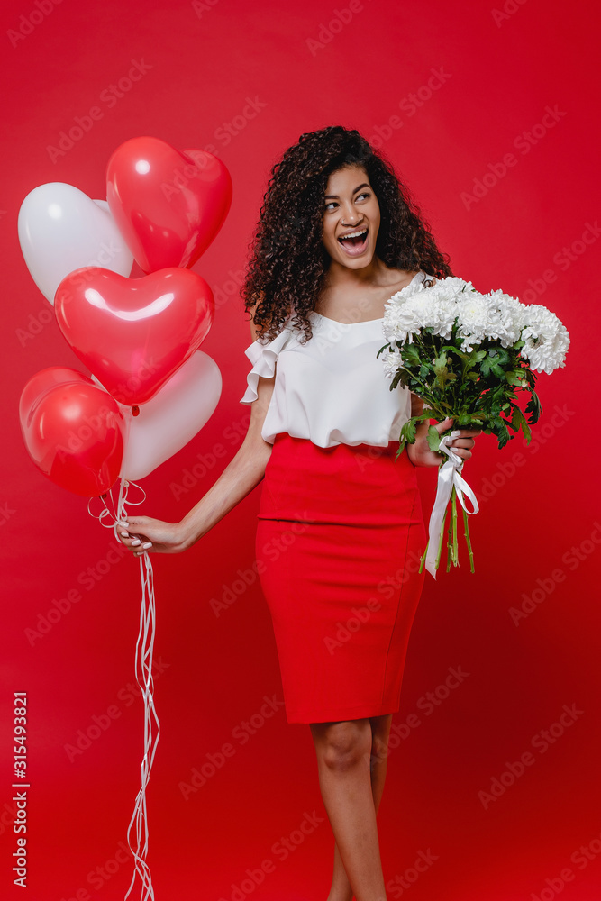 black woman smiling with heart shaped balloons and bouquet of white flowers on red background black woman smiling with heart shaped balloons and bouquet of white flowers on red background