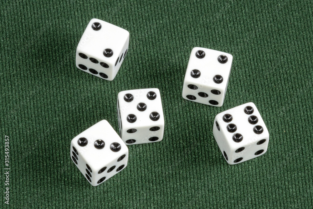 Four Individual white dice on green card table surface Four Individual white dice on green card table surface