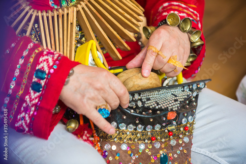 Male hands of a caucasian man, dressed in traditional attire, hold a wooden tap dance instrument.
