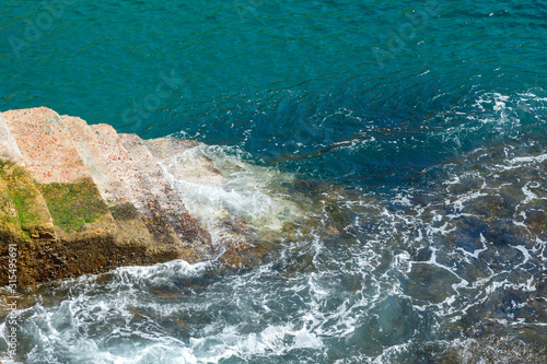 A reliable stone staircase descends into the water of the Atlantic Ocean on a sunny summer day. Sea waves crash on a solid staircase.