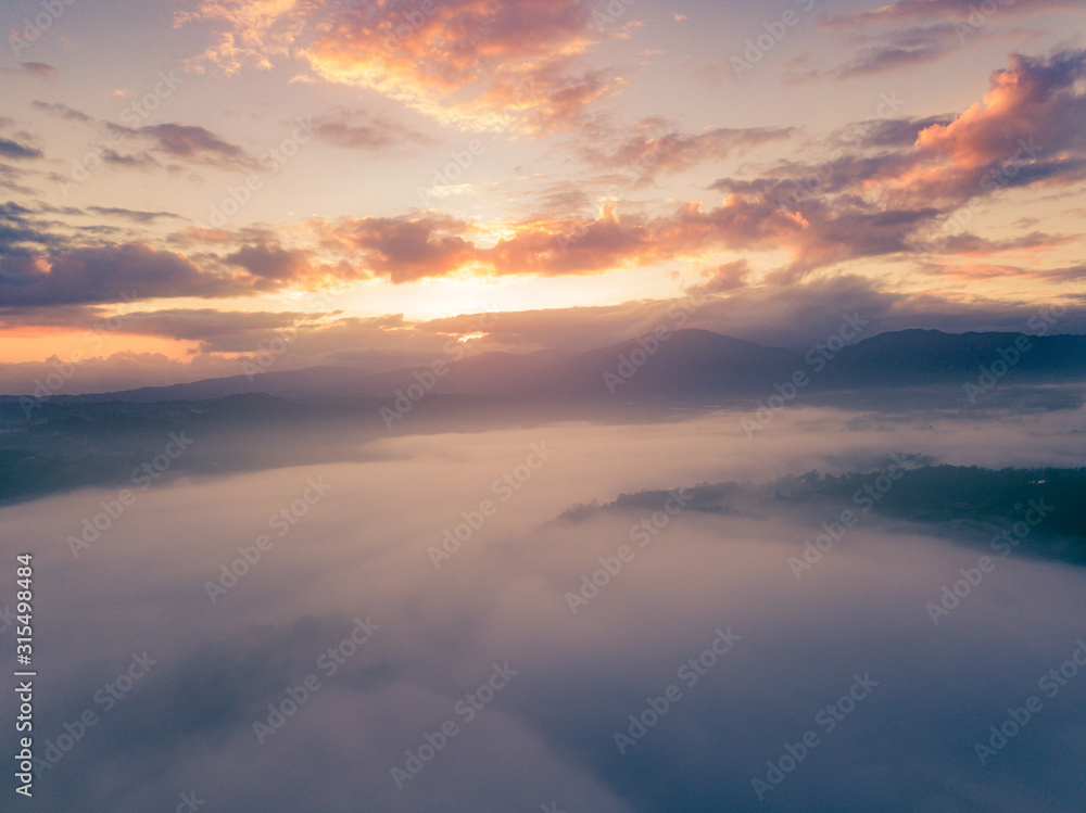 aerial view of orange and yellow glorious sunrise  landscape with mist and fog over the valley of the small town of jarabacoa dominican republic