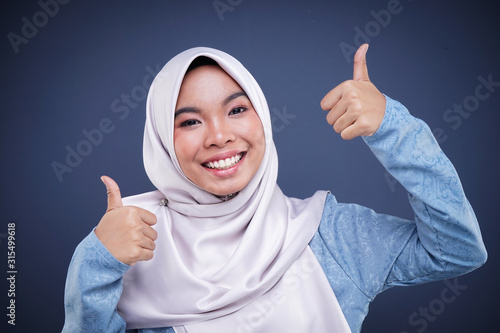 Headshot of a cute Muslim teenager wearing hijab showing various facial expressions isolated on grey background. Landscape orientation.