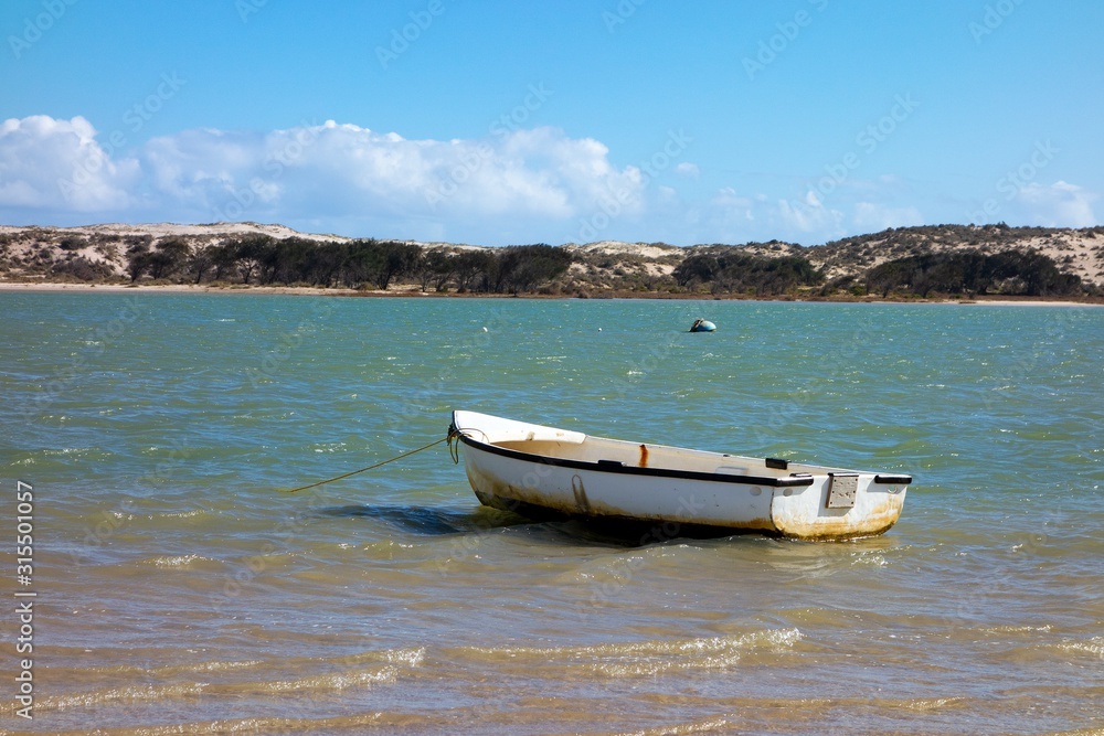 A small white boat left anchored in Lake Magic in Western Australia