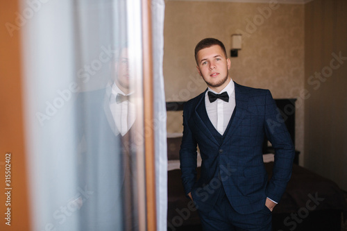 Portrait of handsome young groom in midnight blue sout with bow tie