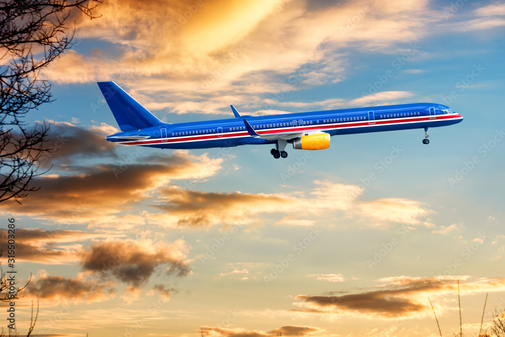 Big blue aeroplane jet is taking-off on background of sunset.