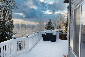 Home outdoor deck closed for the winter with snow on BBQ cooker cover