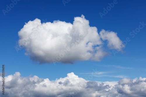 Blauer Himmel mit einer einzelnen Cumuluswolke, die über einer Wolkendecke zu schweben scheint.
