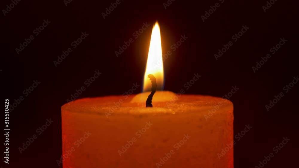 Wide candle flame on black background with red rim light Wide candle flame on black background with red rim light