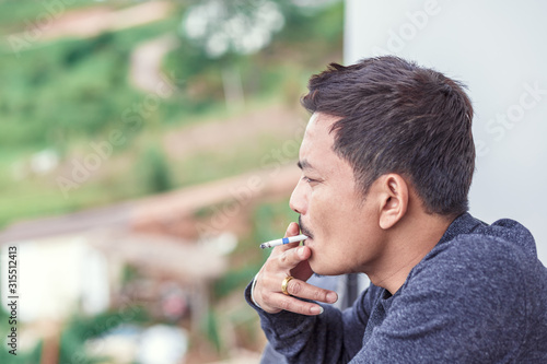 A man smoking on balcony at the hotel.