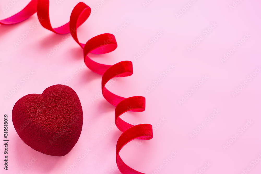 Valentines day concept. Red velvet heart shaped cake on pink surface with red velvet ribbon Valentines day concept. Red velvet heart shaped cake on pink surface with red velvet ribbon