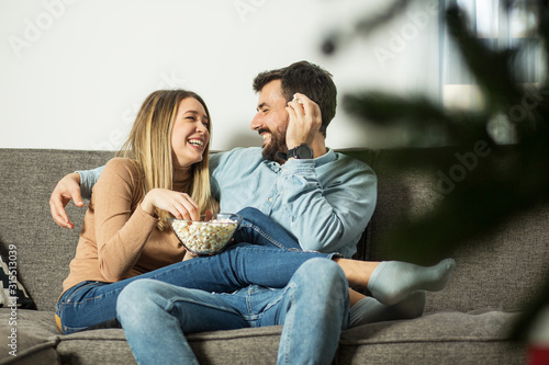 Smiling couple eating popcorn at sofa