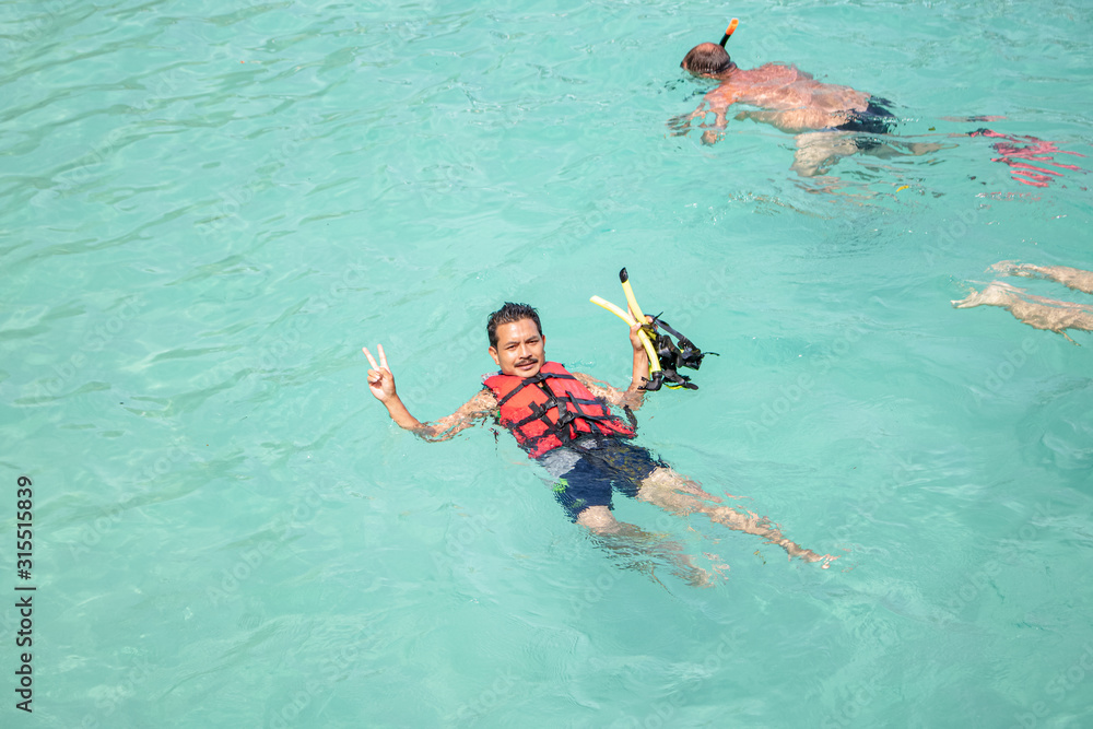 Young man snorkeling in clean water over coral reef. A man wear .Life jacket.