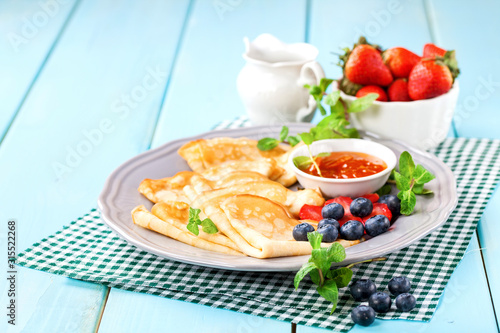 Pancakes with jam and berries on a table. Selective focus. Copy space.