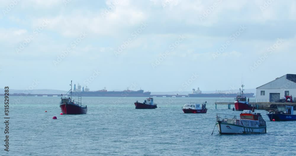 bay with small anchored boats anchors keeping the vessels on fixed location on the peaceful ocean, western Cape, South Africa. Long shot bay with small anchored boats anchors keeping the vessels on fixed location on the peaceful ocean, western Cape, South Africa. Long shot