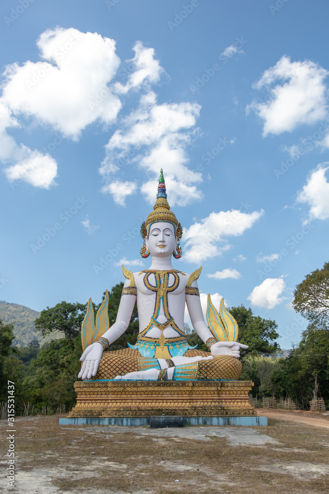 Fototapeta premium Meditation Buddha statue under blue sky with trees around