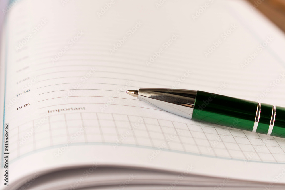 Notepad with a pen on a table. Business supplies. Close up. Notepad with a pen on a table. Business supplies. Close up.