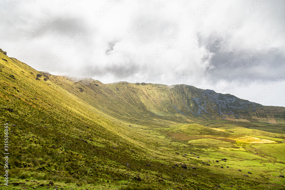 Clouds waft over the southern rim of the Corvo Crater on the island of Corvo in the Azores, Portugal.