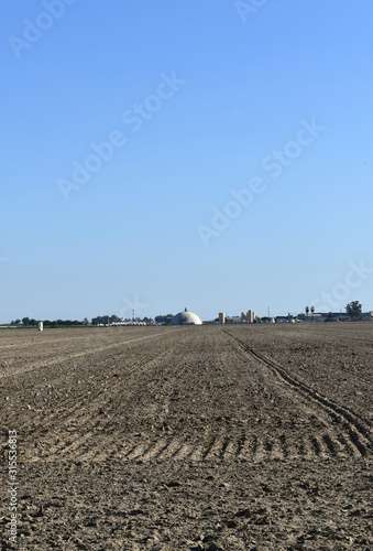 Low view of freshly plowed field in front of ammonia plant