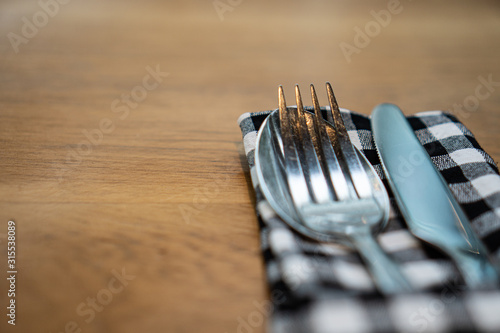 close up knife fork and spoon with napkin on wooden table texture and text space. Background for dining and restaurant. photo