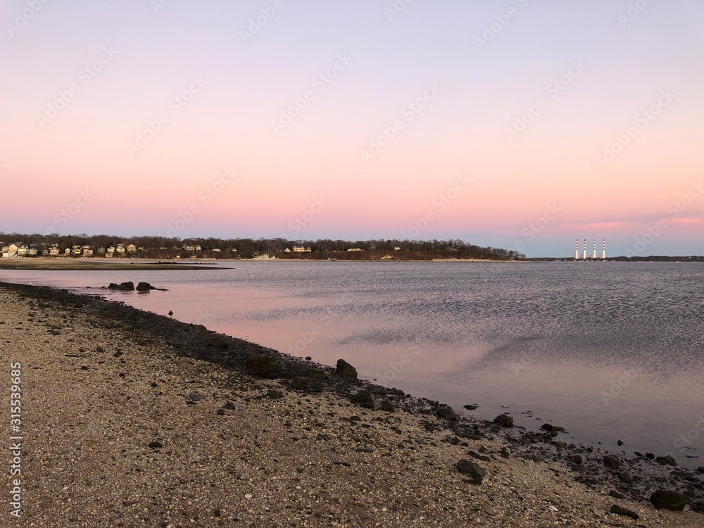 The Northport smokestacks in the distance across the water during a pink sunset.