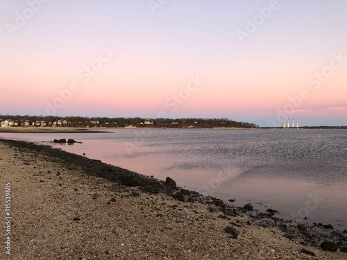 The Northport smokestacks in the distance across the water during a pink sunset.