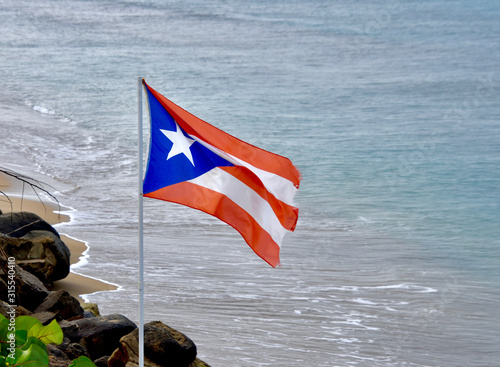 Принти на полотні The flag of Puerto Rico flies over a beach in Rincon