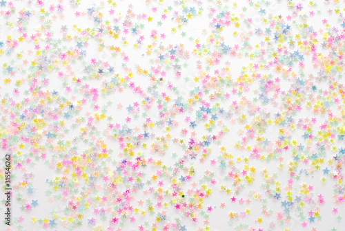 Gold stars confetti abstract pattern on a white background. Holiday concept, top view.