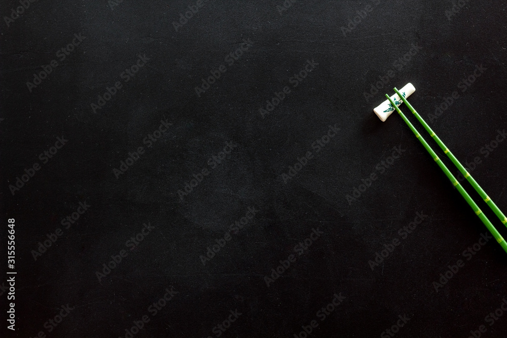 Chopsticks - green wooden utensil for sushi and rolls - on black background top-down copy space Chopsticks - green wooden utensil for sushi and rolls - on black background top-down copy space