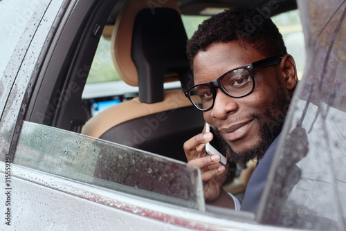 Portrait of a man sitting in the car with a phone by the ear.