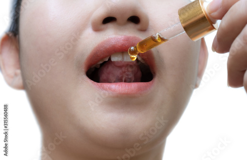 Woman holding a dropper sublingual Cannabis oil at white background photo