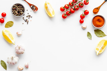 Kitchen frame with spices and food - pepper, garlic, cherry tomatoes - on white background top-down frame copy space