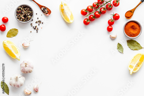 Kitchen frame with spices and food - pepper, garlic, cherry tomatoes - on white background top-down frame copy space