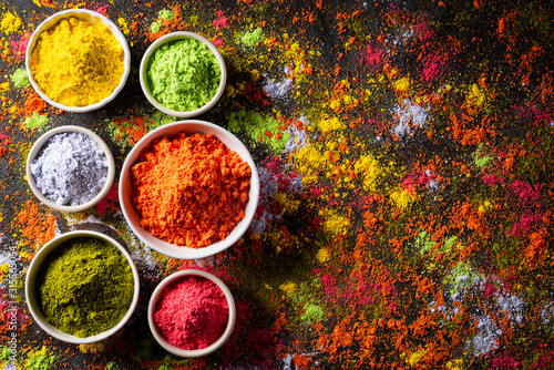 Holi festival celebration. Traditional Indian Holi colours powder decoration with paints. Top view of Organic Gulal colors in bowls, spices, rustic background for Holi festival. © Siam
