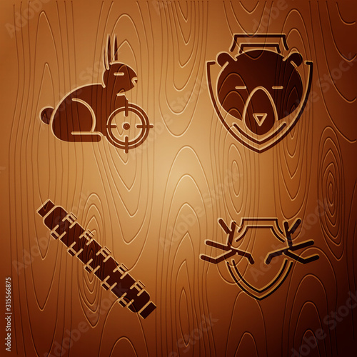 Set Deer antlers on shield, Hunt on rabbit with crosshairs, Hunting cartridge belt with cartridges and Bear head on shield on wooden background. Vector
